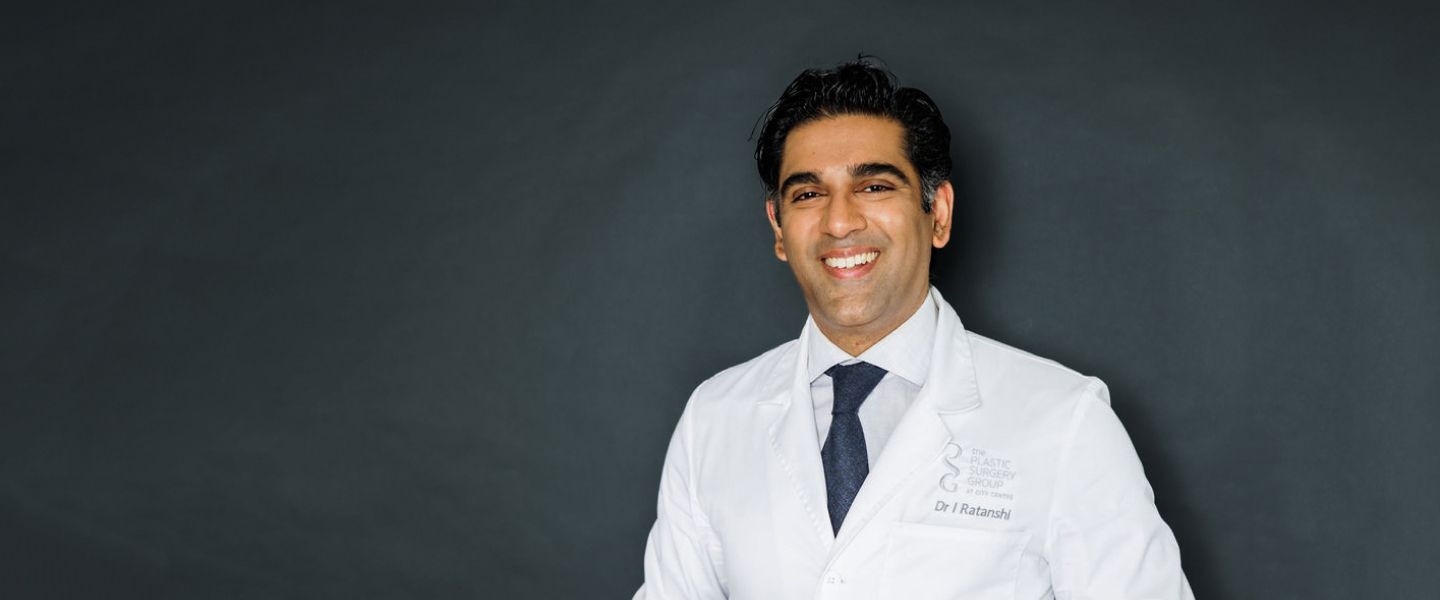 Smiling doctor in white coat against dark background